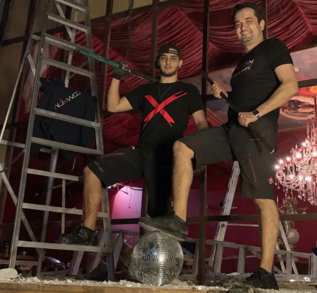 Volkan mit Vorschlaghammer und Gregor mit Brechstange auf einer Baustelle